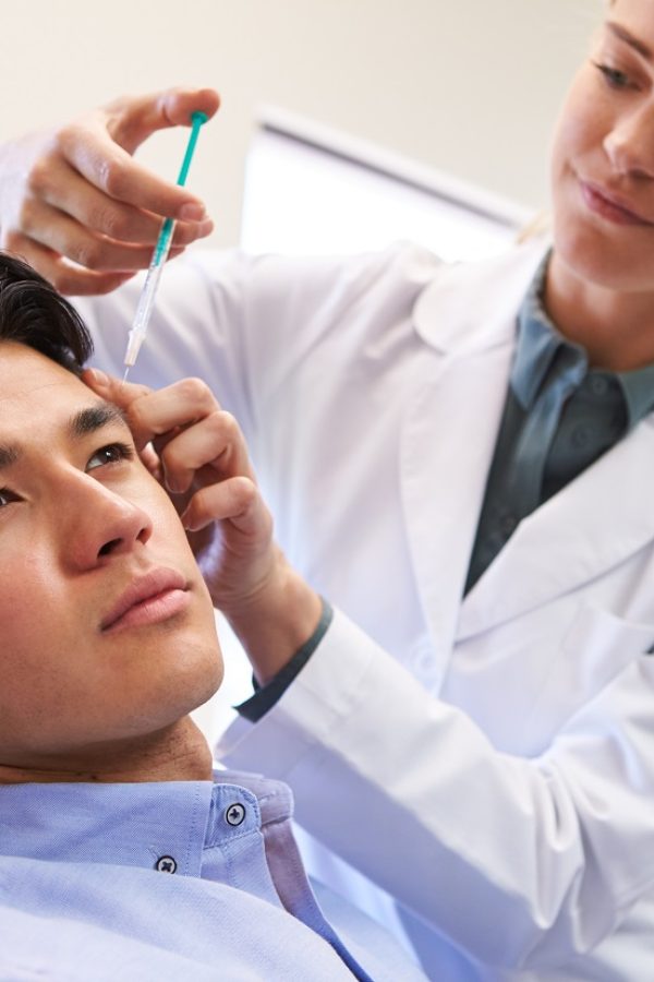 Man Sitting In Chair Being Give Botox Injection By Female Doctor